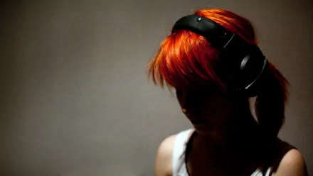 A silhouette of Hayley Williams wearing headphones, showcasing her vibrant orange hair. This HD wallpaper captures the essence of her music with Paramore.