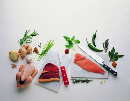 HD PC desktop wallpaper showing an array of fresh raw meats, herbs, spices, and knives arranged on a white background.