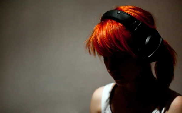 A silhouette of Hayley Williams wearing headphones, showcasing her vibrant orange hair. This HD wallpaper captures the essence of her music with Paramore.