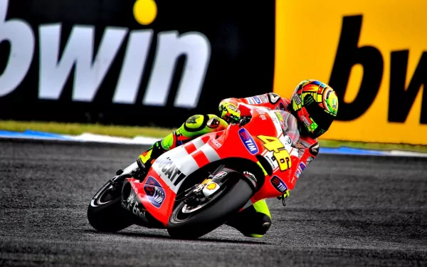 HD PC desktop wallpaper and background: a red Ducati racing vehicle leaning sharply through a turn, rider in vivid racing kit with sponsor billboards lining the track.