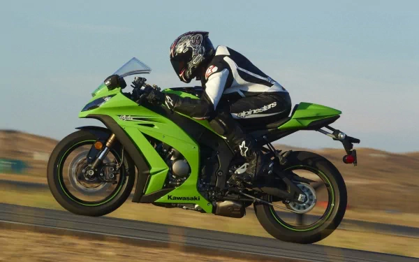 HD PC desktop wallpaper of a green Kawasaki Ninja ZX-10R sportbike, rider in full gear leaning through a turn on a racetrack with a motion-blurred desert landscape.
