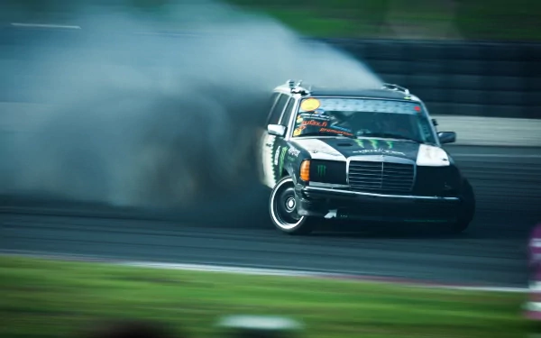 A dynamic HD wallpaper featuring a Mercedes vehicle drifting on a track, surrounded by smoke, showcasing its powerful performance in an exhilarating moment.