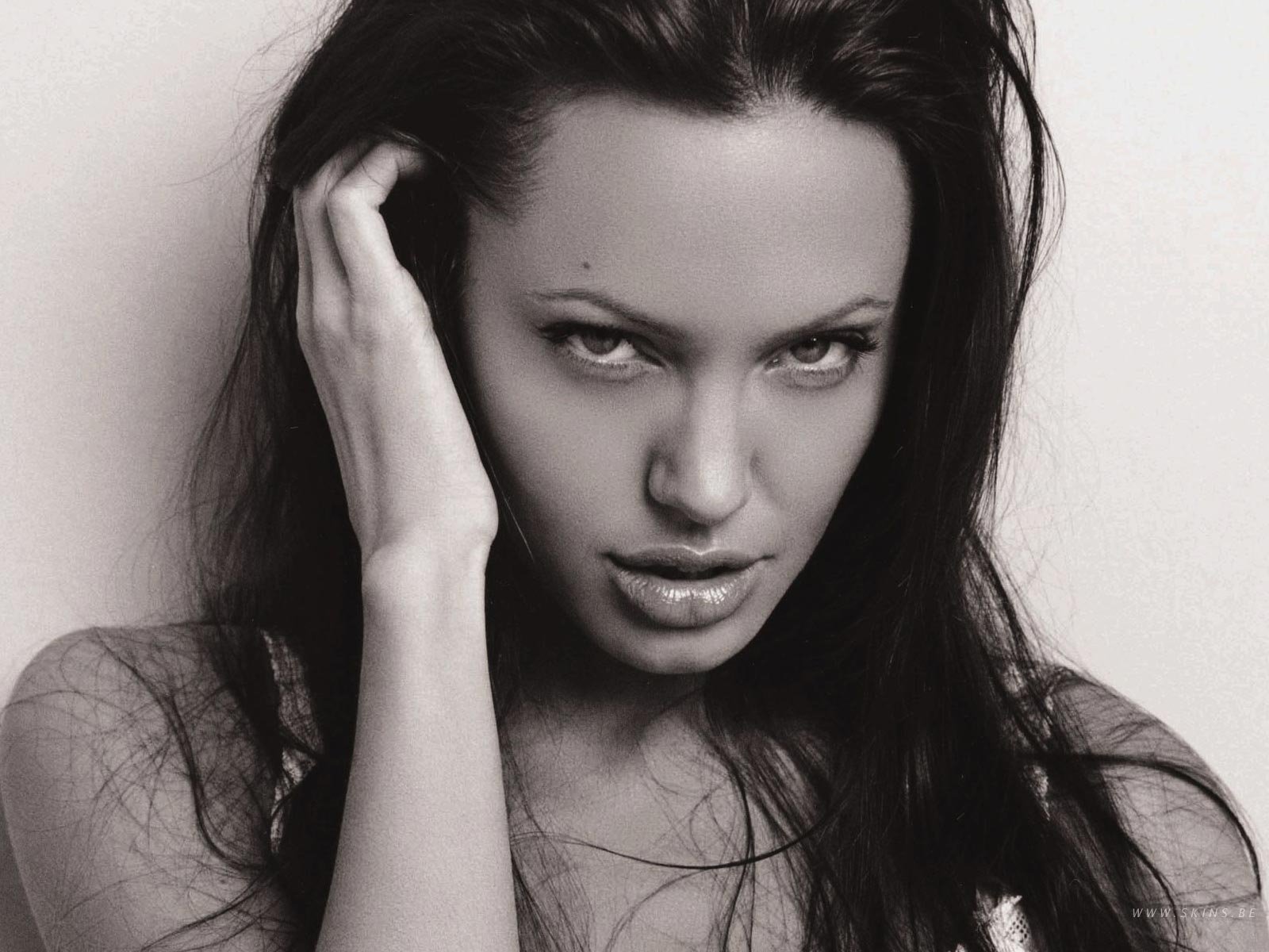 A striking black and white portrait of Angelina Jolie, showcasing her captivating expression and long hair, serves as a stunning HD desktop wallpaper and background.