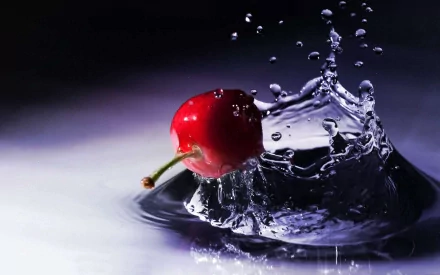 HD desktop wallpaper featuring a vibrant red cherry splashing into clear water, highlighting freshness and vivid detail against a dark background.