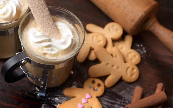 HD PC desktop wallpaper featuring creamy coffee topped with whipped cream, surrounded by gingerbread cookies and a wooden rolling pin on a rustic wooden surface.
