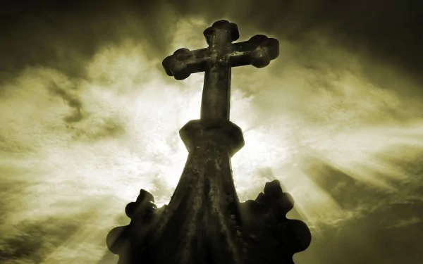 Silhouetted cross against a dramatic sky, radiating light from behind, creating a striking Christian-themed background for your desktop wallpaper.