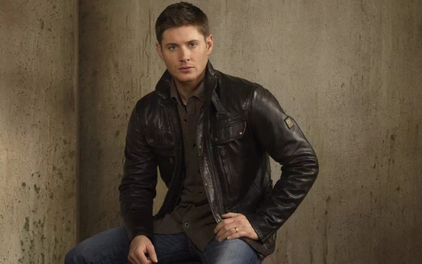 HD PC desktop wallpaper featuring celebrity Jensen Ackles wearing a dark leather jacket against a textured beige background.