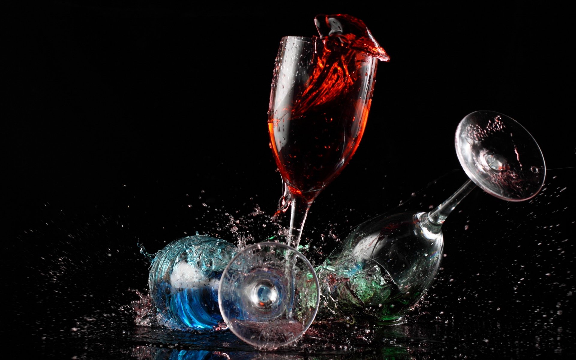 Artistic close-up of colorful liquid splashing from a tall glass among tipped wine glasses, captured in vivid detail for an HD PC desktop wallpaper and background.