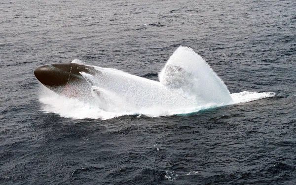 4K Ultra HD desktop wallpaper of a military submarine surfacing rapidly, creating large splashes in the open ocean.