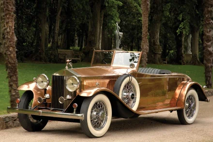 A classic Rolls-Royce vehicle in a stunning copper finish, parked in a lush, green setting, showcasing elegant design. HD desktop wallpaper and background.