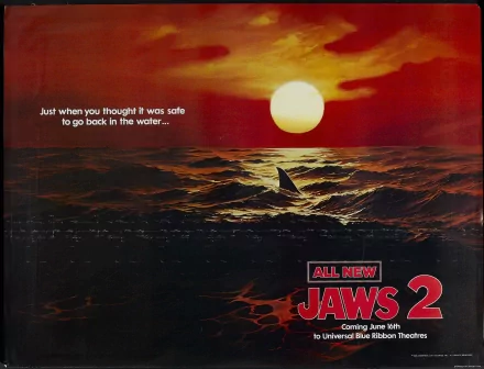 Jaws 2 movie 2K Quad HD PC desktop wallpaper: fiery sunset over choppy ocean, a shark fin slicing the waves beneath a bright sun, tagline on left and Jaws 2 logo at bottom right.