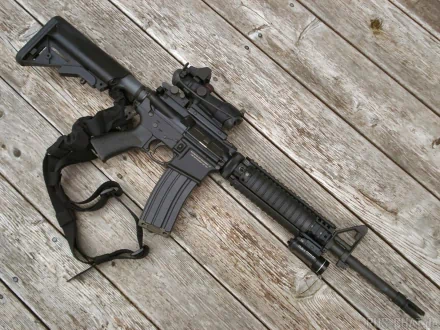 HD PC desktop wallpaper: a man-made black assault rifle with sling laid diagonally on weathered wooden planks.