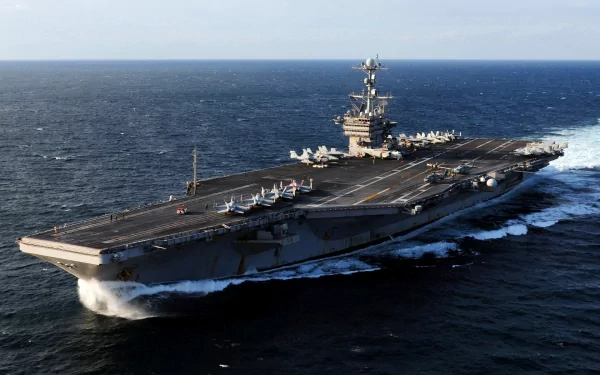 An HD image of the USS George Washington (CVN-73), a military aircraft carrier, navigating through open waters, showcasing its large deck and warship features.
