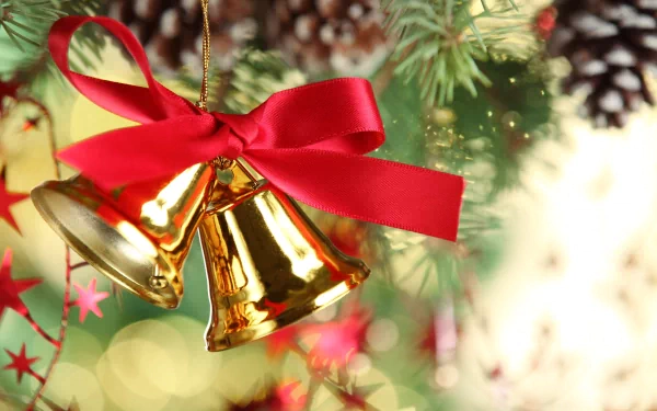 Shiny golden Christmas bells tied with a red ribbon hang on a pine branch, adorned with festive holiday ornaments, captured in a vibrant 4K Ultra HD desktop wallpaper.