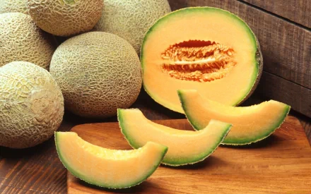 HD PC desktop wallpaper featuring fresh cantaloupe melons, including whole melons and slices arranged on a wooden surface.