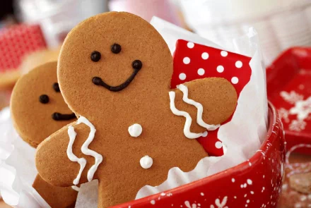 Close-up of smiling gingerbread cookies in a red polka-dot holiday container, captured in 4K Ultra HD for a festive Christmas PC desktop wallpaper.