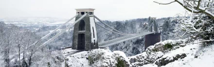 Snow-dusted Clifton Suspension Bridge spanning the frosted Avon Gorge near Bristol — HD desktop wallpaper of the man-made landmark.