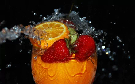 HD PC desktop wallpaper featuring a refreshing drink with orange slices and strawberries splashed with water against a black background.