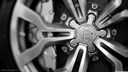 Black-and-white 4K Ultra HD PC desktop wallpaper of a close-up Audi vehicle alloy wheel hub and spokes, focused on the central Audi logo.