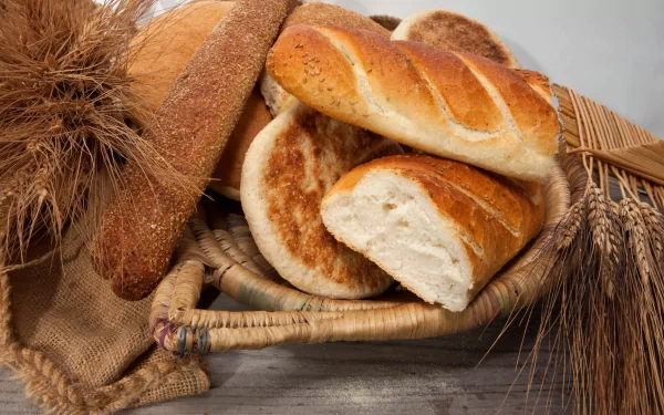 HD desktop wallpaper featuring an assortment of fresh bread loaves and wheat stalks arranged in a basket, highlighting rustic food and bread themes.