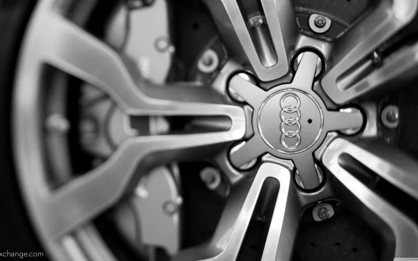 Black-and-white 4K Ultra HD PC desktop wallpaper of a close-up Audi vehicle alloy wheel hub and spokes, focused on the central Audi logo.