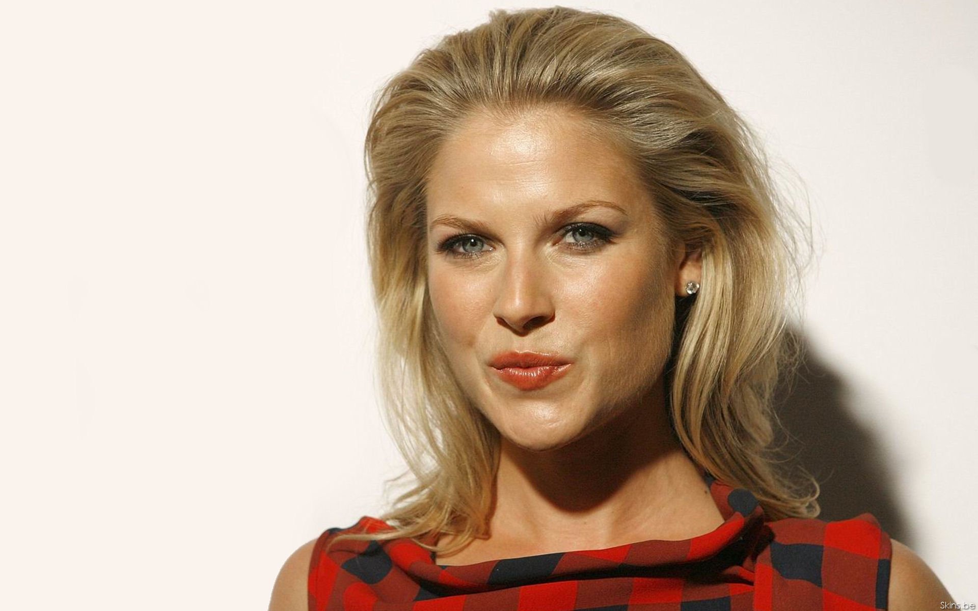 HD desktop wallpaper featuring celebrity Ali Larter with blonde hair wearing a red and black patterned top against a neutral background.