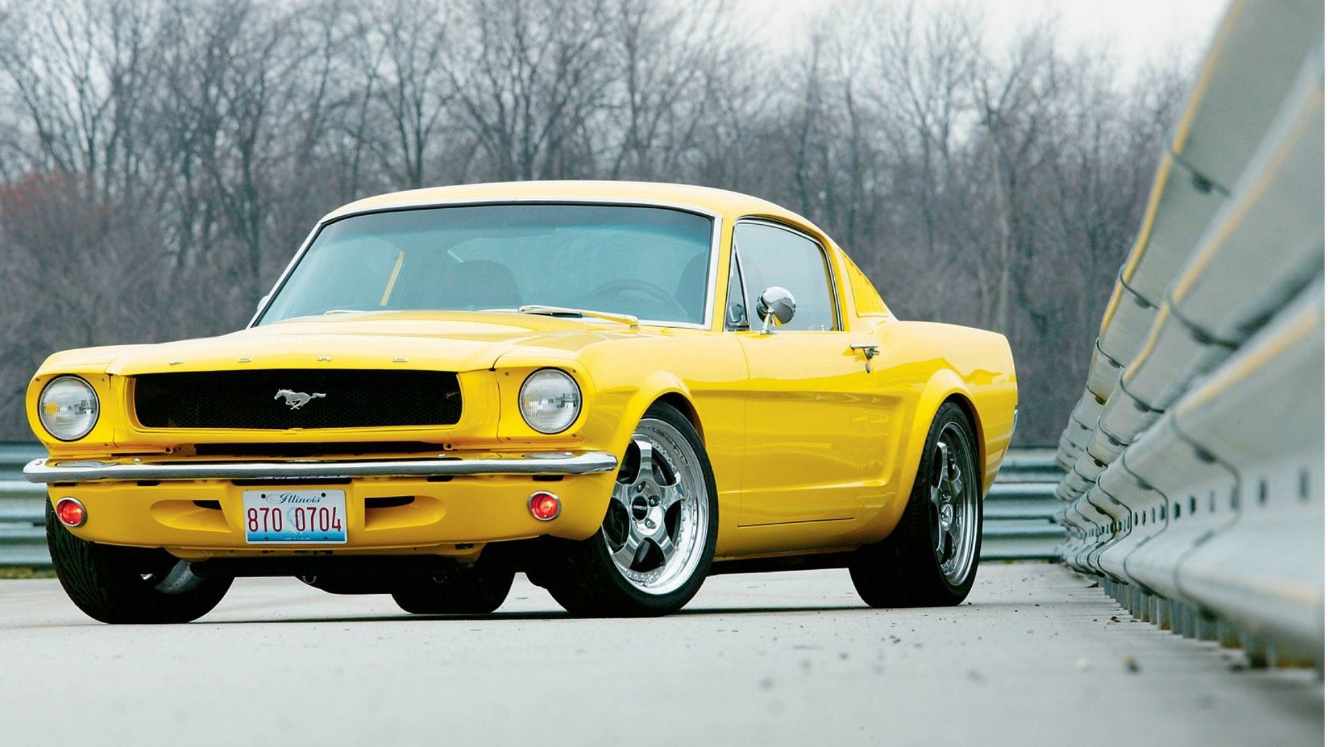Yellow Ford Mustang parked on a road next to a metal guardrail, featured as an HD PC desktop wallpaper and background.