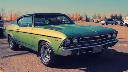 HD desktop wallpaper featuring a vibrant green Chevrolet Chevelle SS parked in a lot with autumn trees in the background.