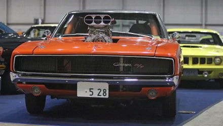 HD desktop wallpaper featuring a bold orange Dodge Charger with a prominent engine blower, showcased in a car exhibition setting.
