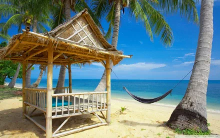 HD PC desktop wallpaper/background — holiday beach photography of a bamboo hut and palm-hung hammock on golden sand with turquoise sea and clear blue sky.