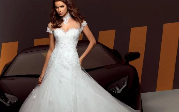 HD PC desktop wallpaper featuring celebrity Irina Shayk in an elegant white gown standing in front of a black sports car with a striped background.