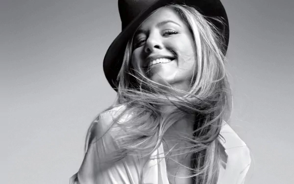 Black and white HD desktop wallpaper featuring celebrity Jennifer Aniston smiling with windblown hair and wearing a wide-brimmed hat.