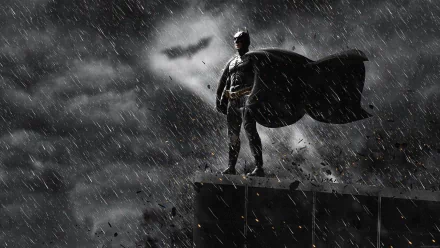 HD PC desktop wallpaper of Batman standing on a rooftop in the rain with the bat symbol in the cloudy sky, from the movie The Dark Knight Rises.