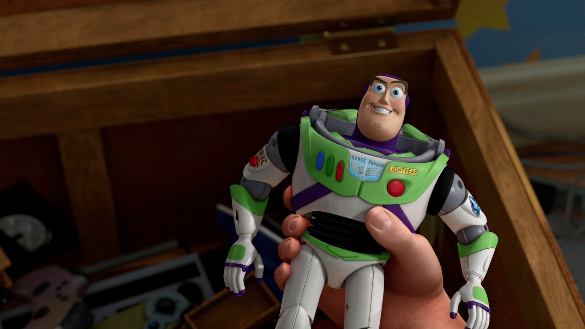 A hand holds a Buzz Lightyear toy, showcasing the iconic character from the movie Toy Story against a backdrop of a wooden toy chest. This HD image makes a playful desktop wallpaper.