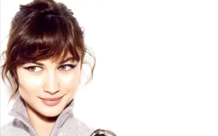 HD PC desktop wallpaper featuring celebrity Olga Kurylenko with a soft smile and tousled hair against a clean white background.