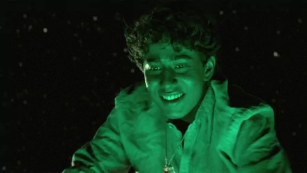 HD PC wallpaper of a smiling boy from the movie Life of Pi, joyful expression lit in green against a dark, star-speckled background.