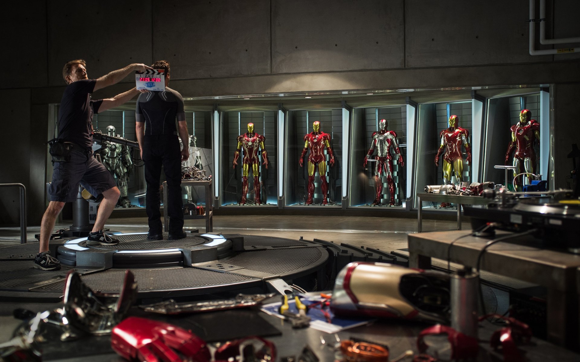 HD PC desktop wallpaper featuring Tony Stark and multiple Iron Man suits from the movie Iron Man 3 in a high-tech workshop setting.