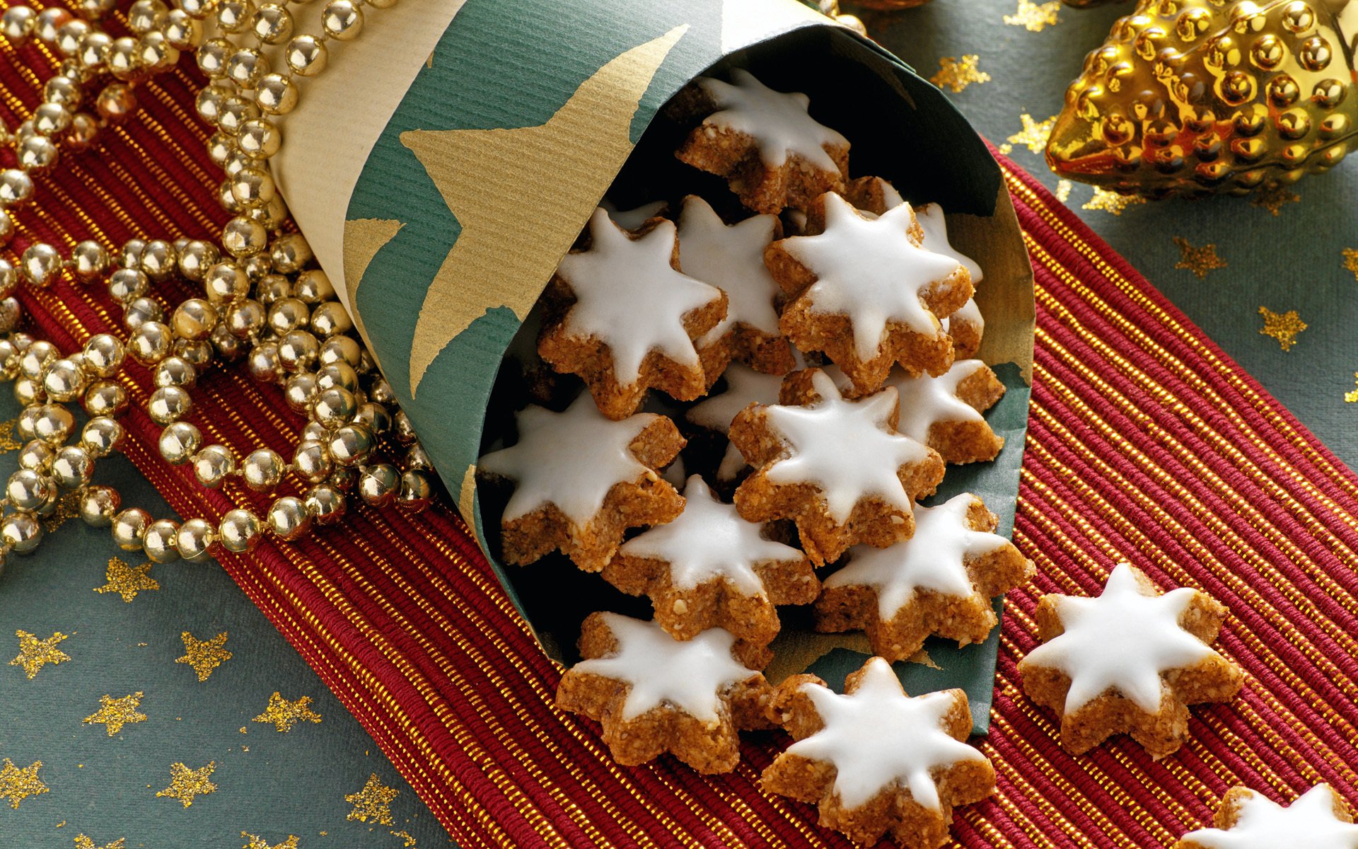 A festive scene featuring star-shaped cookies spilling from a decorated paper cone, surrounded by shimmering Christmas ornaments and golden beads, capturing the holiday spirit beautifully.