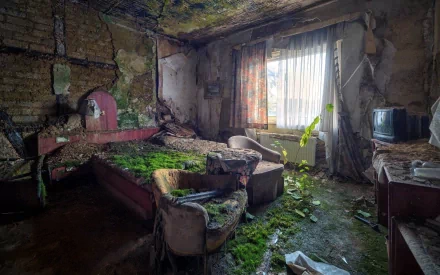 HD desktop wallpaper of a man-made ruin featuring an abandoned, moss-covered room with decayed furniture and light filtering through a window.