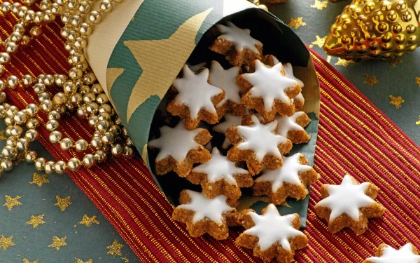 A festive scene featuring star-shaped cookies spilling from a decorated paper cone, surrounded by shimmering Christmas ornaments and golden beads, capturing the holiday spirit beautifully.