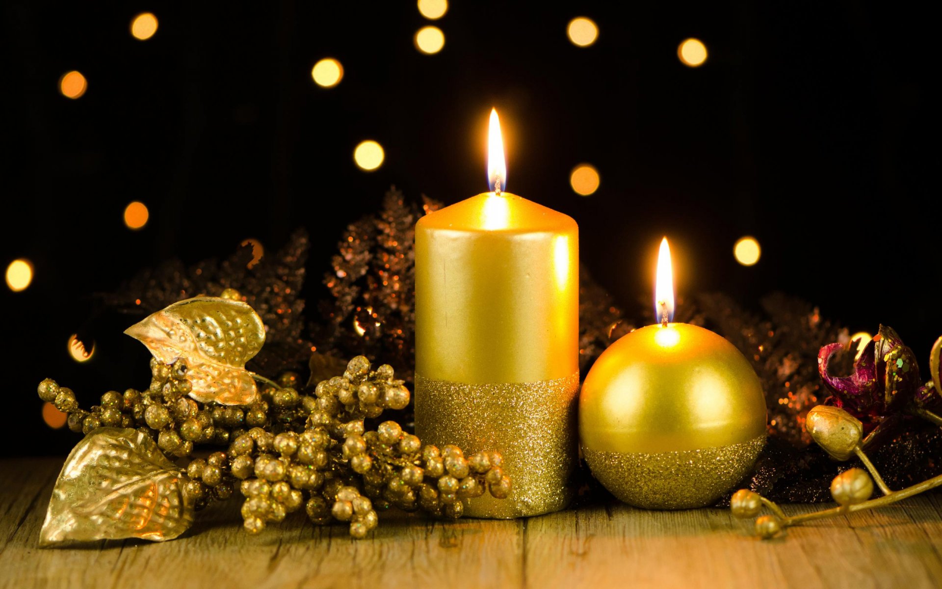 HD PC desktop wallpaper featuring glowing gold Christmas candles surrounded by holiday decorations with warm bokeh lights in the background.