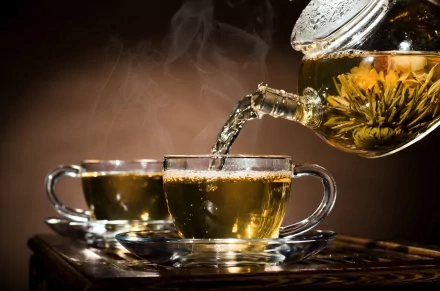 A vibrant HD desktop wallpaper featuring steaming tea being poured into two glass cups, highlighting the warmth and inviting nature of freshly brewed tea.