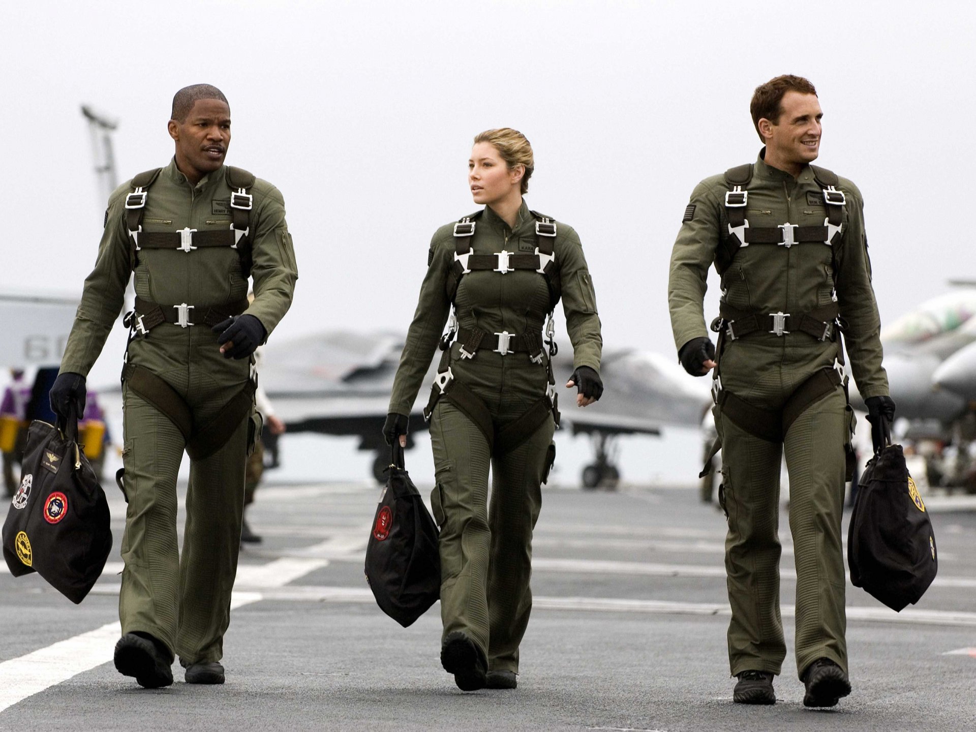 HD PC desktop wallpaper from the movie Stealth, featuring three pilots walking confidently on an aircraft carrier deck in flight suits.
