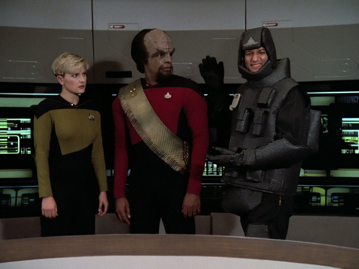 HD desktop wallpaper featuring Q, Tasha Yar, and Worf from Star Trek: The Next Generation in their iconic Starfleet uniforms aboard the USS Enterprise.