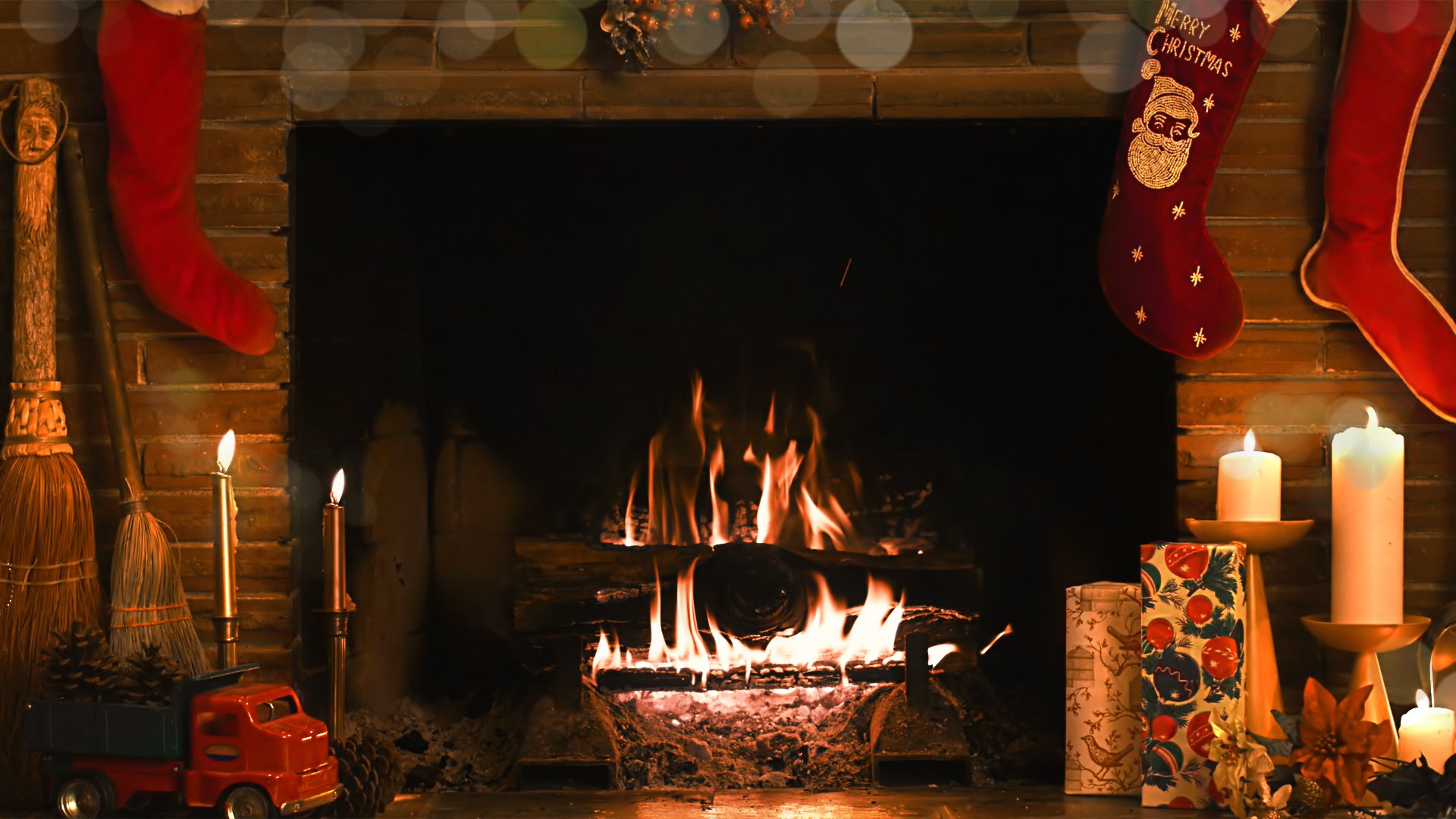 A cozy fireplace adorned with holiday stockings, flickering candles, and festive decorations, creating a warm Christmas atmosphere. This HD wallpaper brings holiday cheer to any desktop.