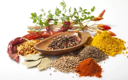 HD desktop wallpaper featuring an assortment of herbs and spices, including dried chili, peppercorns, turmeric, and bay leaves arranged on a white background.