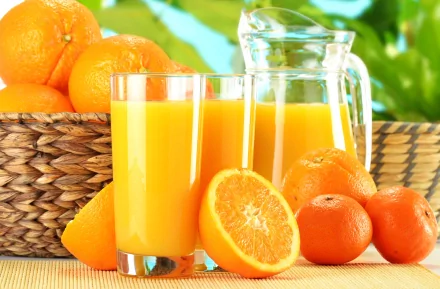 A vibrant 4K Ultra HD desktop wallpaper featuring fresh orange juice in glasses and a pitcher, surrounded by whole and halved oranges in a bright, natural setting.