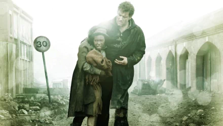 HD wallpaper of a scene from Children Of Men featuring Clive Owen in a protective stance with a child in a dystopian setting.
