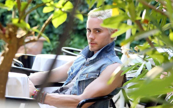 2K Quad HD PC desktop wallpaper: moody music portrait of a seated man in a denim vest among leafy greenery, tagged Thirty Seconds to Mars.