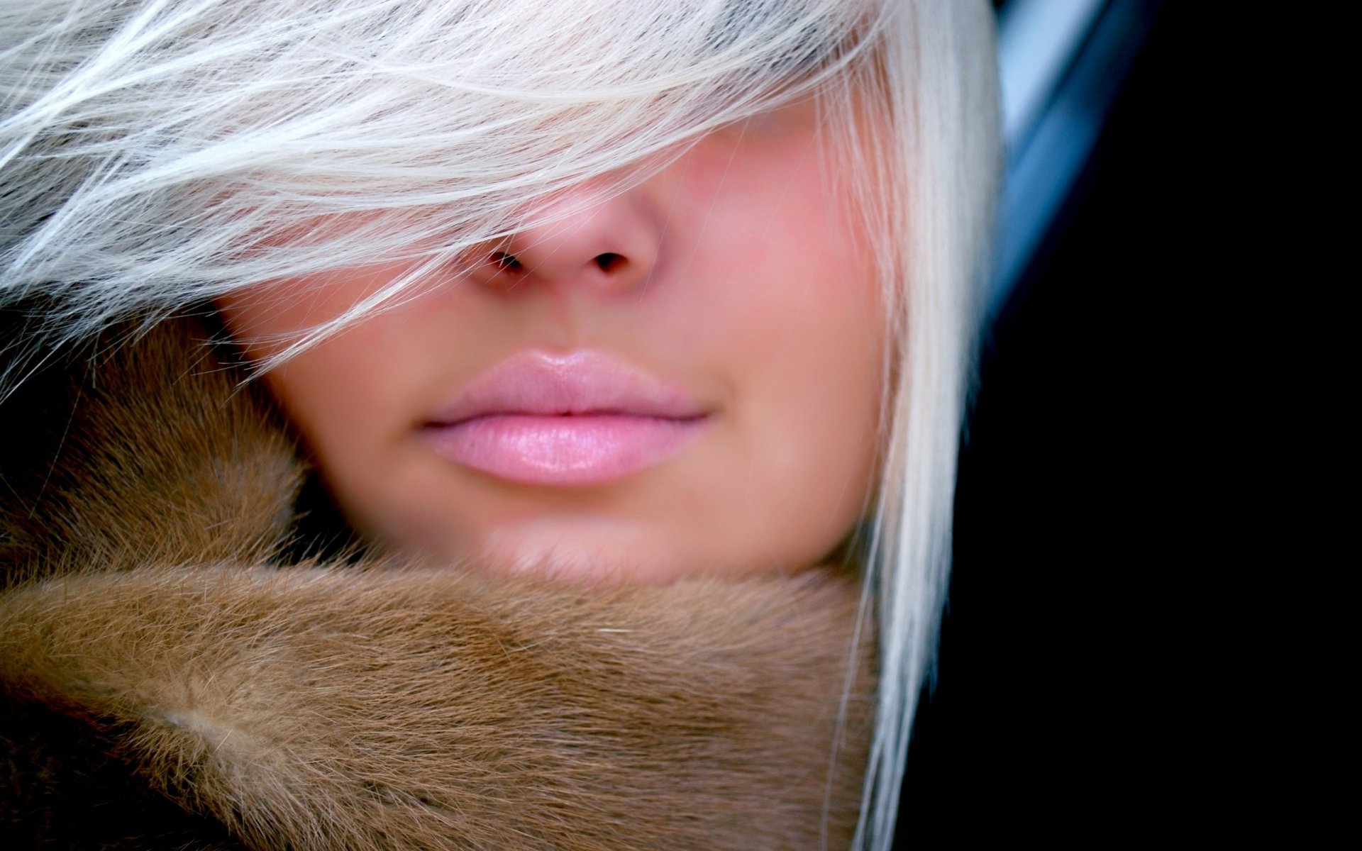 Close-up of a woman’s lips partially obscured by soft, flowing hair, with a warm brown fur collar. This HD image can serve as a striking desktop wallpaper or background.